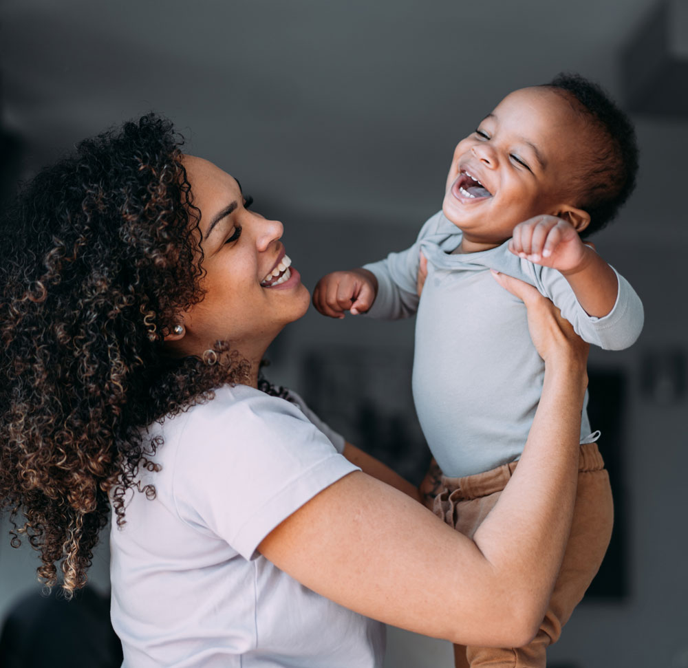 Smiling woman holds laughing baby indoors