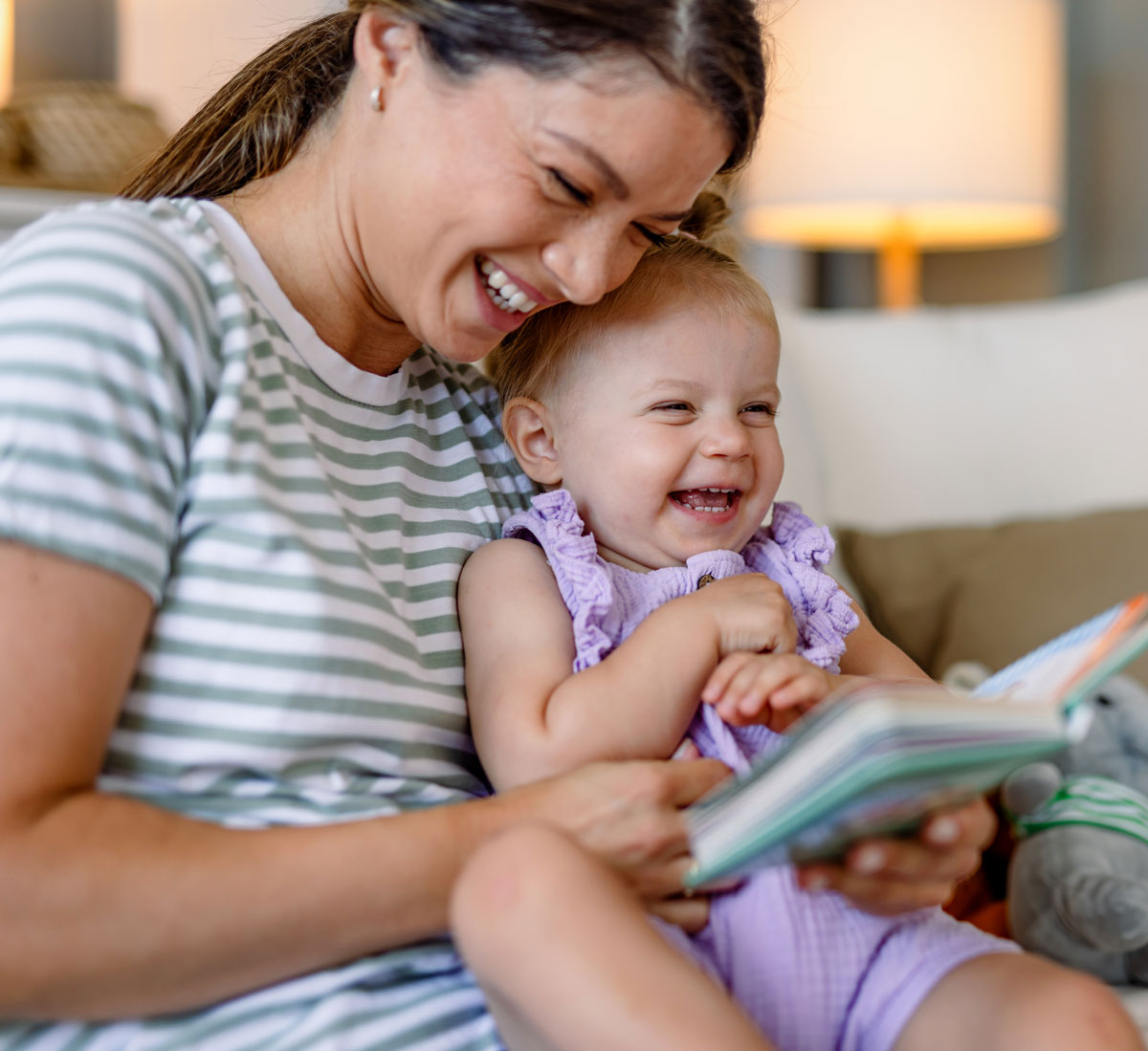 Mother and child laughing while reading a book
