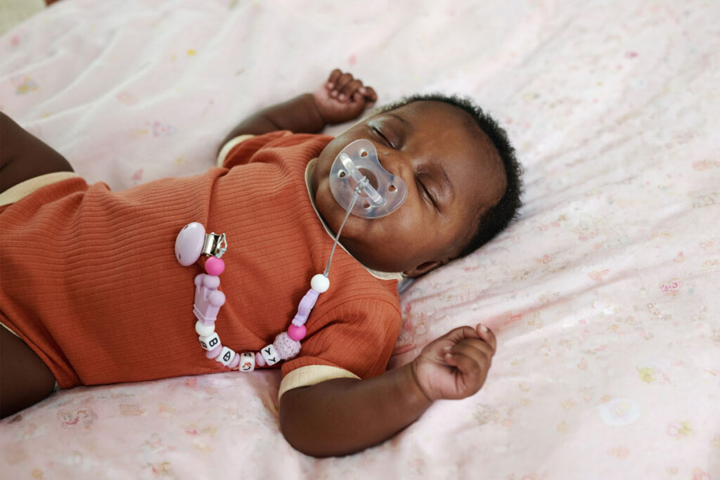 Sleeping baby with pacifier on floral blanket