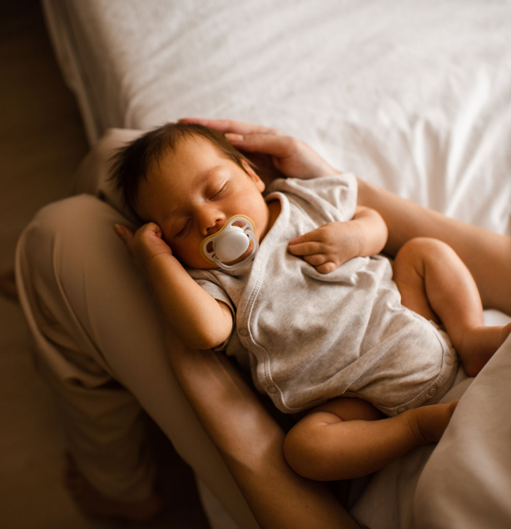 Sleeping baby with pacifier cradled in arms