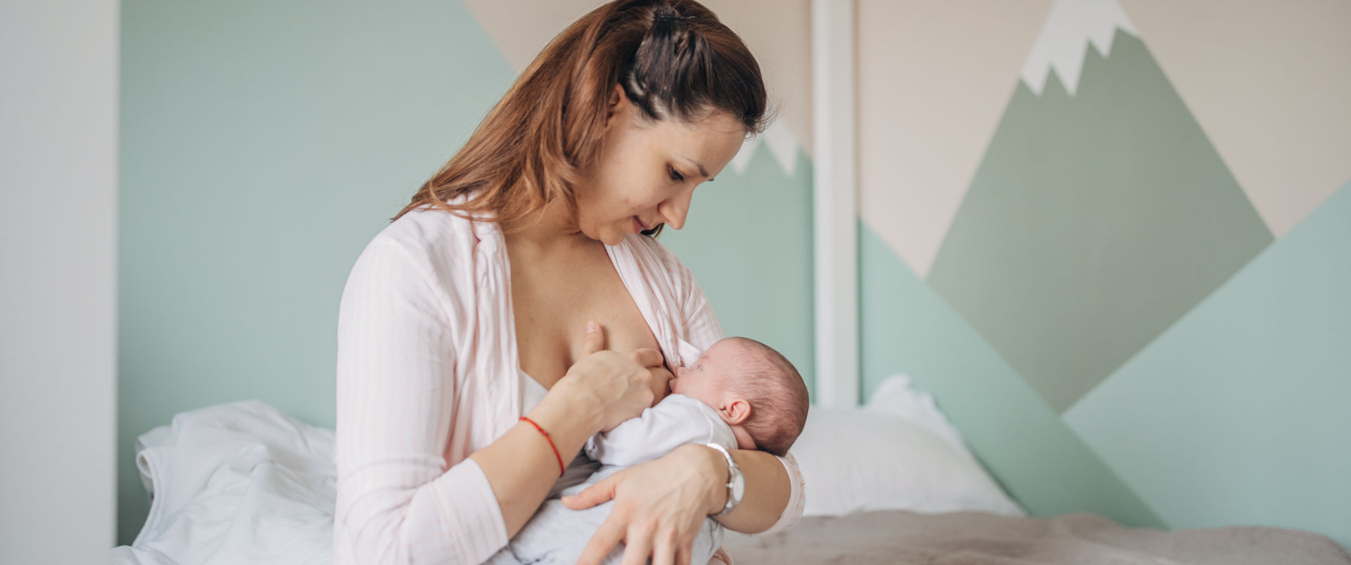 Mother breastfeeding newborn baby on a bed