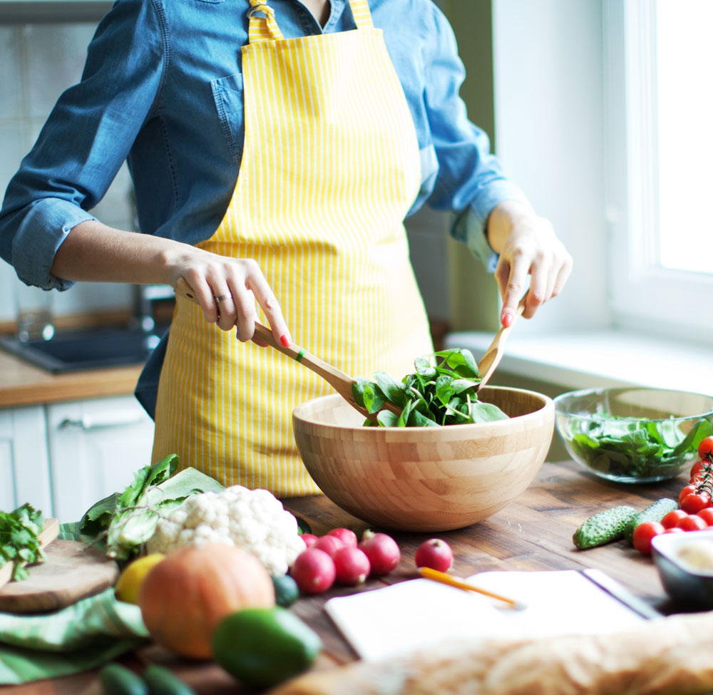 Woman-tossing-fresh-salad-in-wooden-bowl