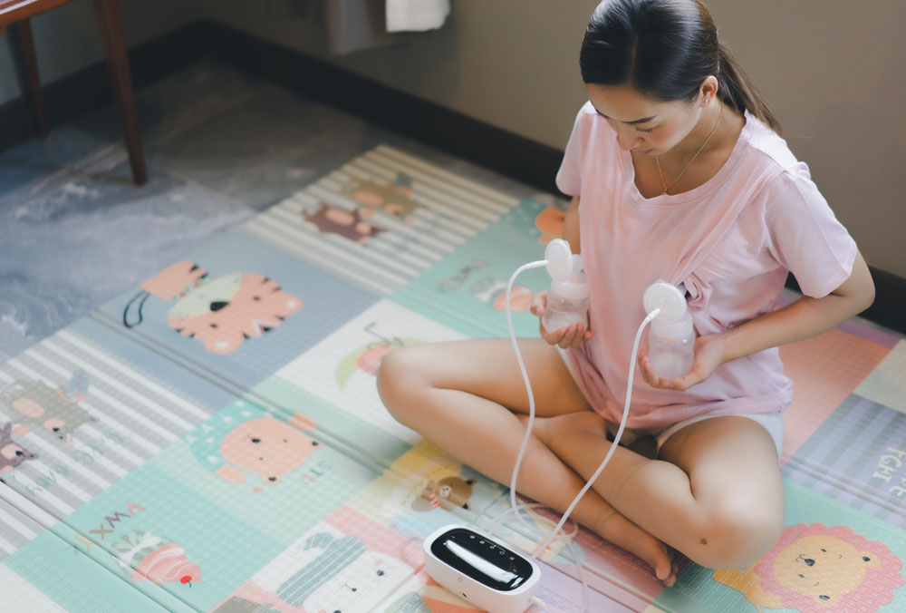 Woman using breast pump on colorful play mat
