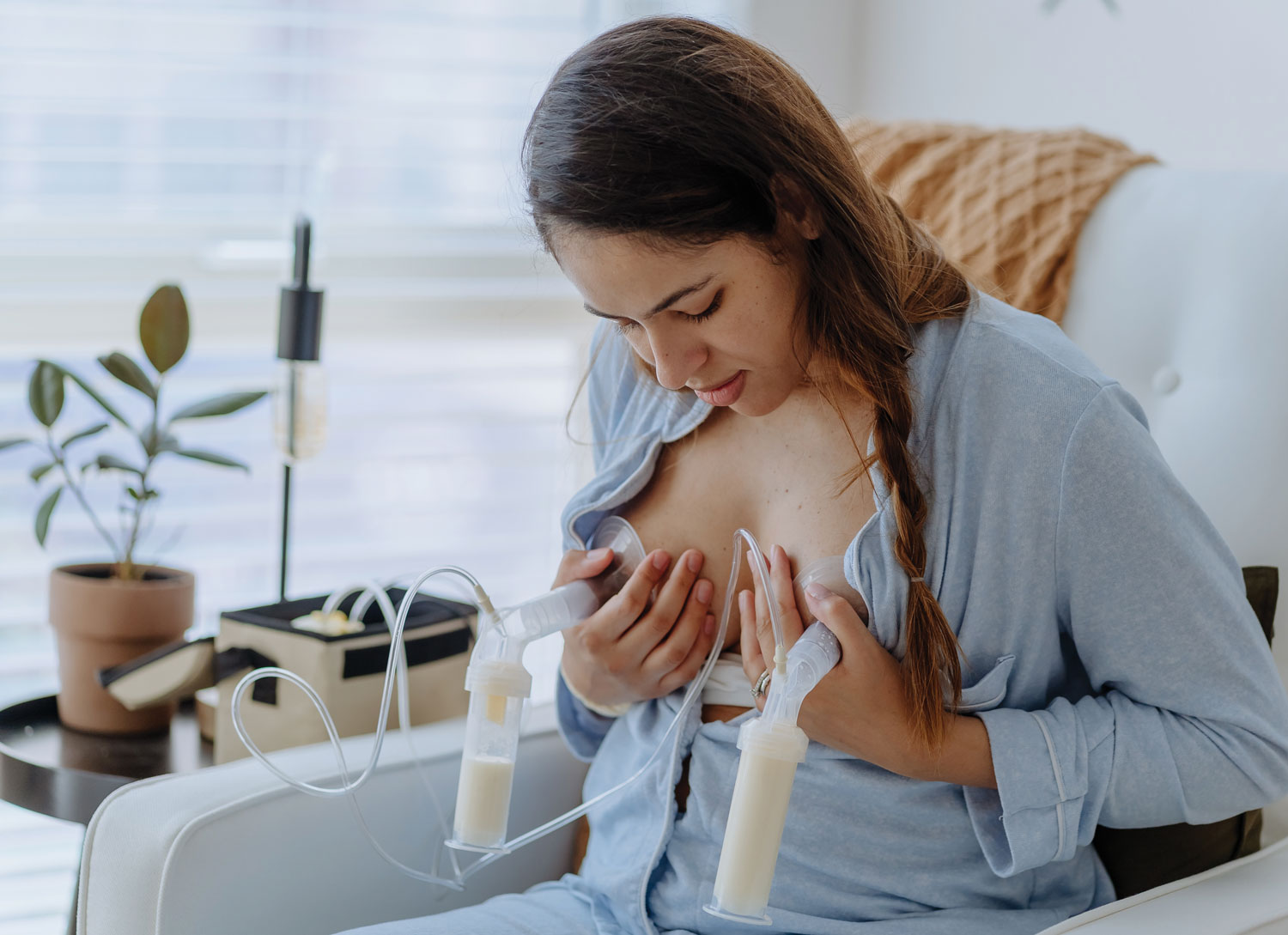 Woman using breast pump on chair