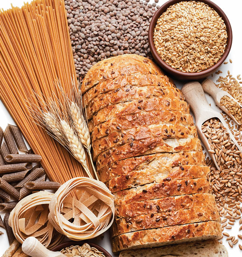 Sliced bread surrounded by various grains and pasta.