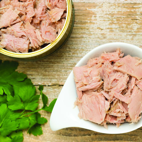 Canned tuna in bowl next to fresh parsley.