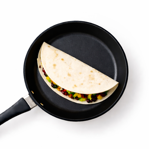Tortilla with vegetables cooking in a black pan.