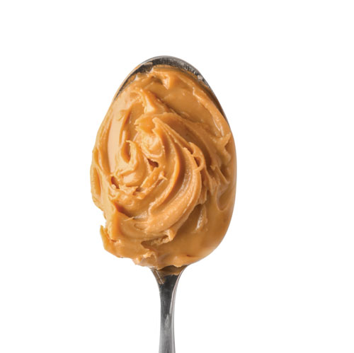 Spoonful of creamy peanut butter isolated on white.