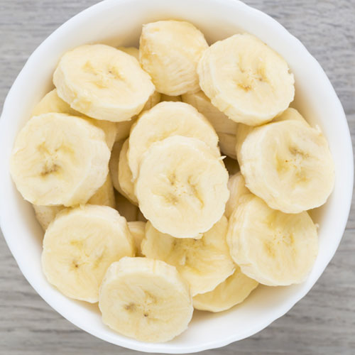 Sliced bananas in a white bowl.