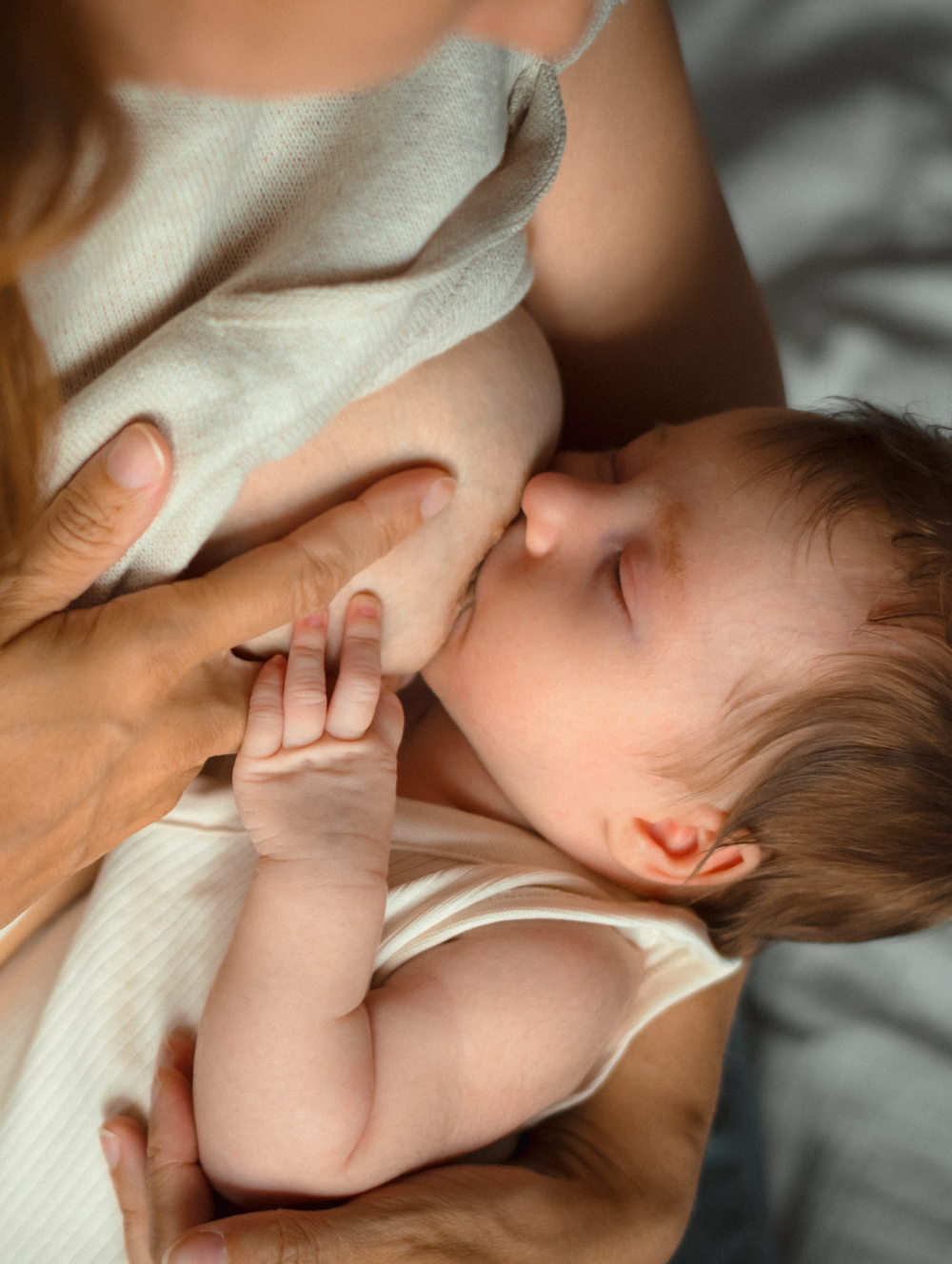 Baby breastfeeding in mothers arms for nourishment