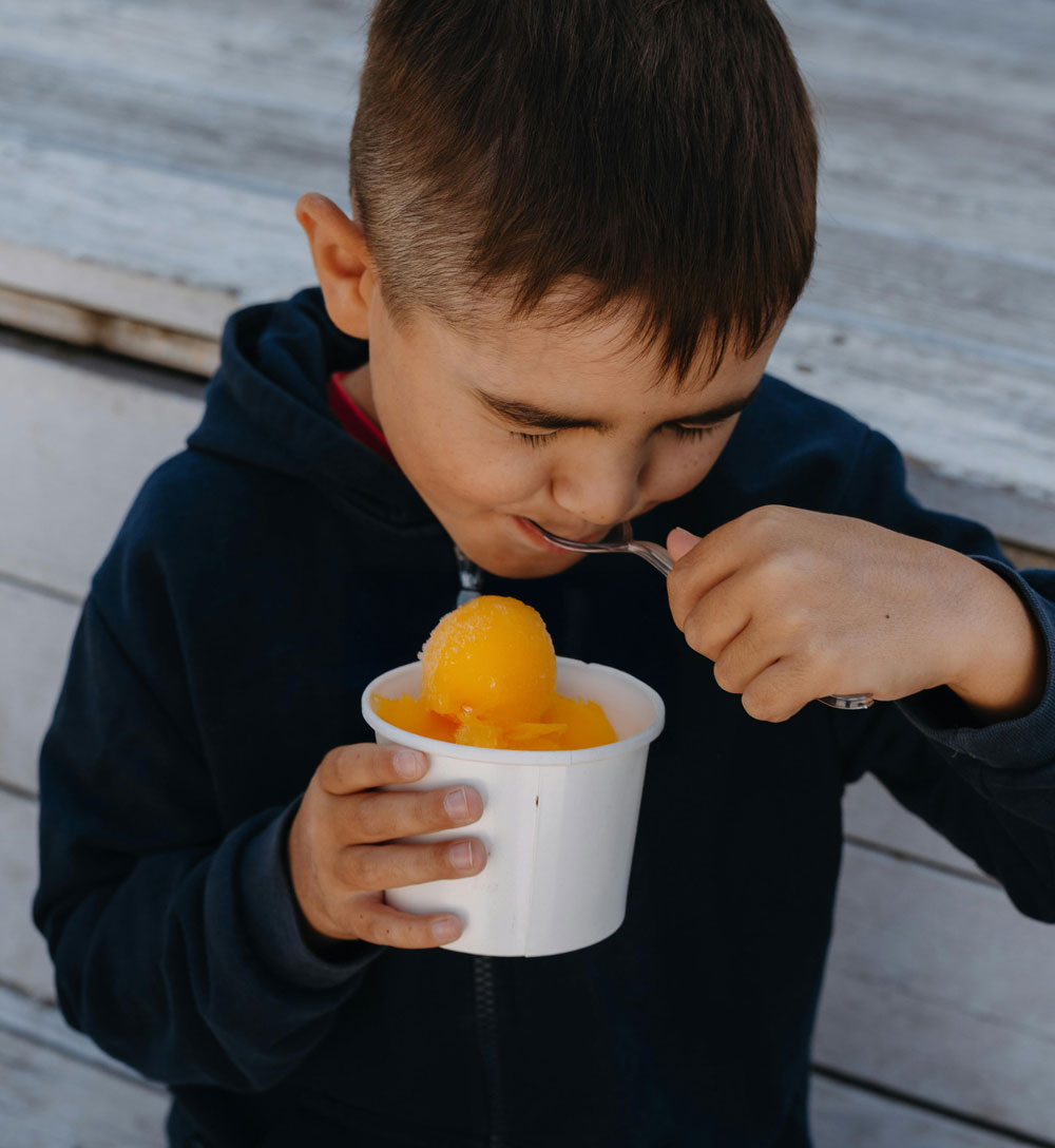 Child eating frozen treat from a cup