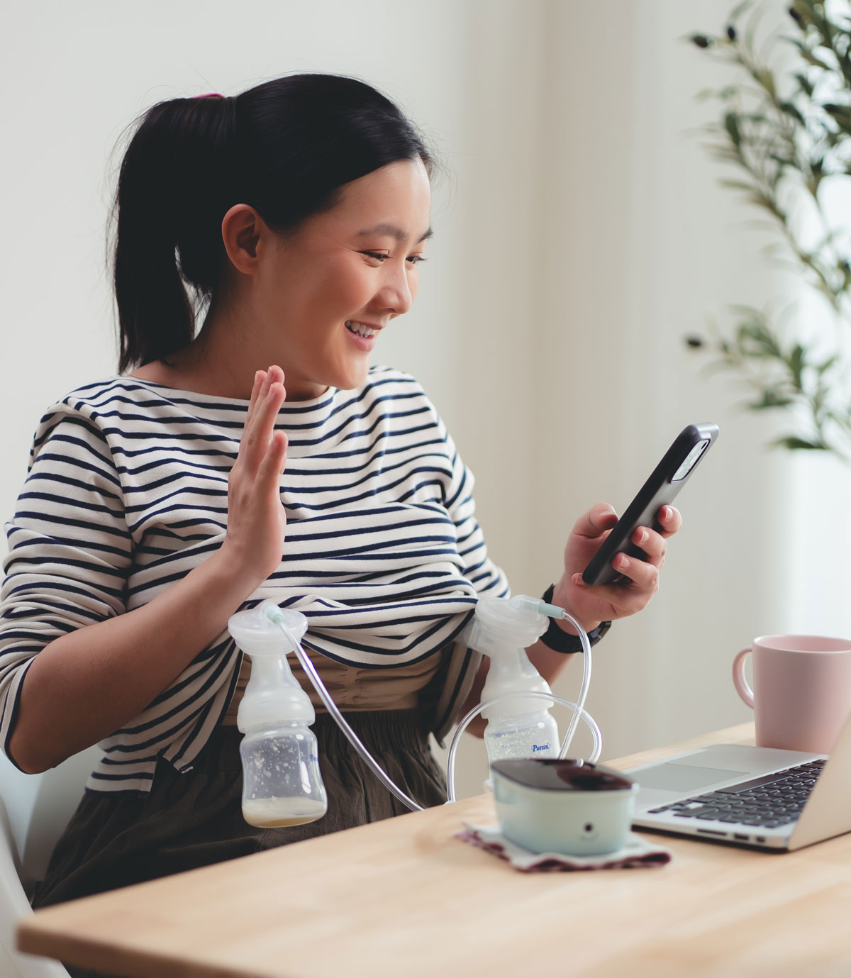 Woman multitasking with breast pump and smartphone