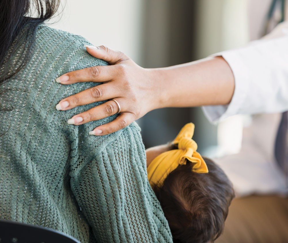 Hand comforts woman with baby on shoulder