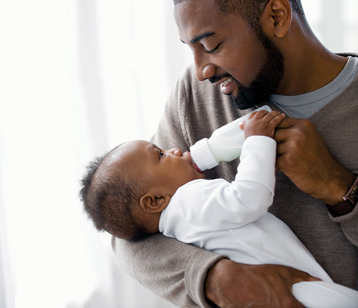 Man cradles baby while bottle-feeding gently