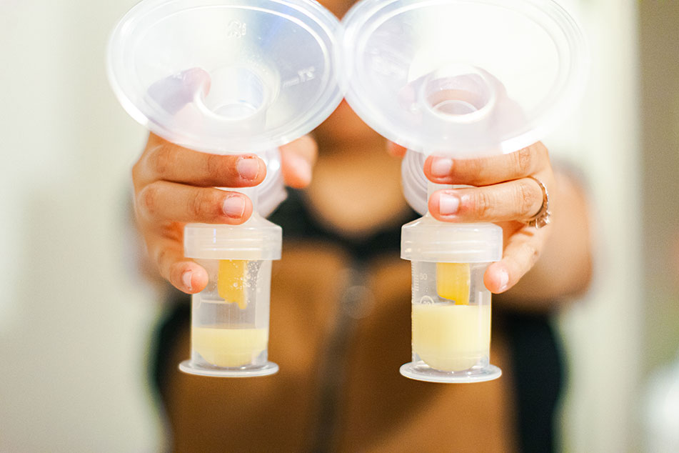 Hands holding breast pump with expressed milk