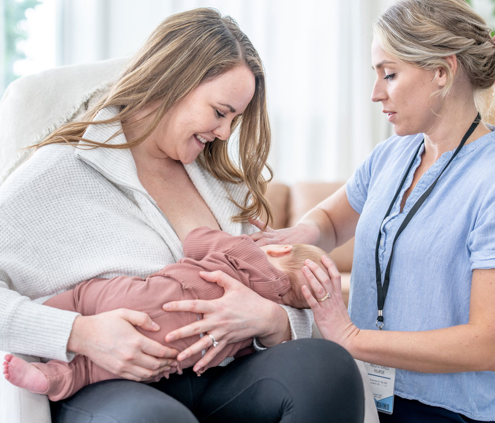 Nurse assisting mother breastfeeding her baby