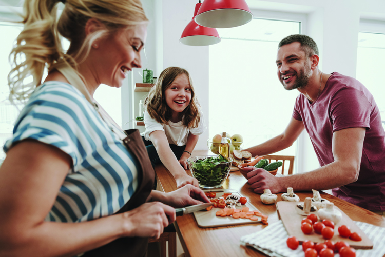 Family joyfully preparing vegetables together in kitchen