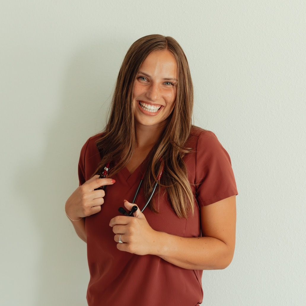 Smiling woman with stethoscope, wearing maroon scrubs