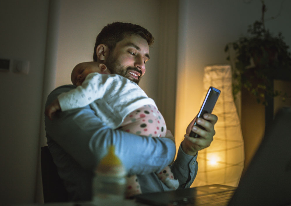 Father holding baby and using smartphone