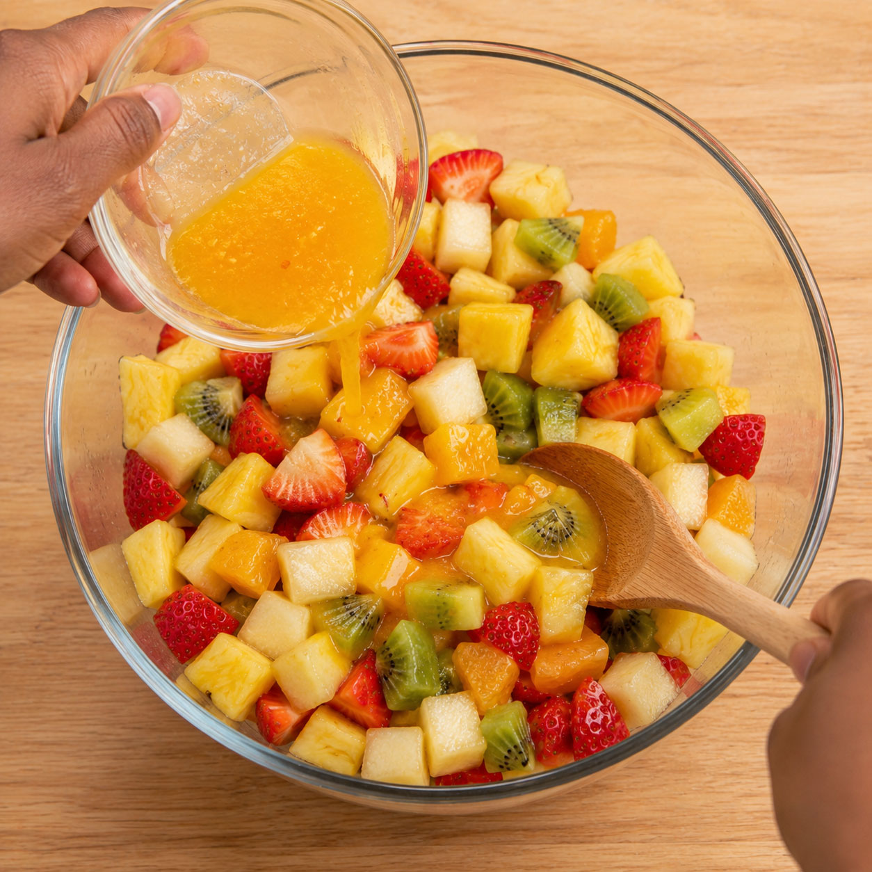 Adding orange glaze to mixed fruit bowl