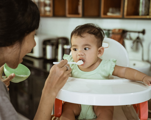 Mom Feeding Asian Baby High Chai